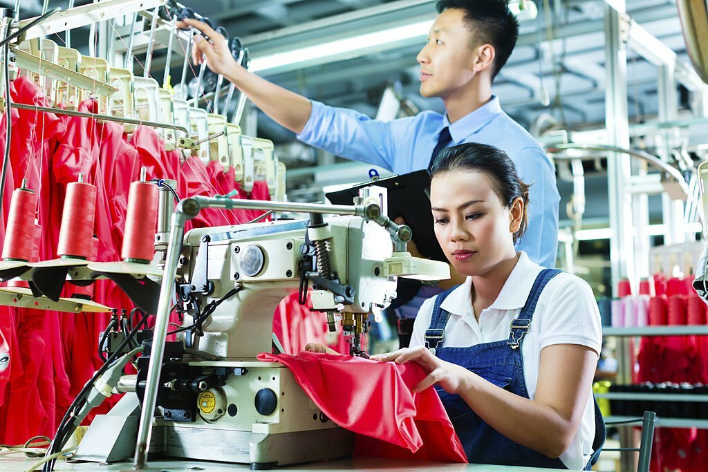 Seamstress or worker in a factory sewing with a sewing machine